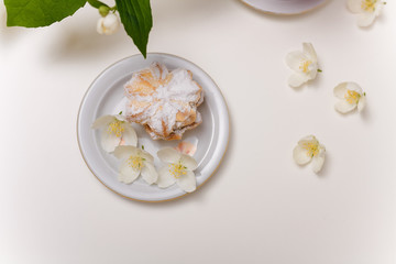 Obraz na płótnie Canvas cake with jam and powdered sugar on the plate with spring jasmine flowers on the white background