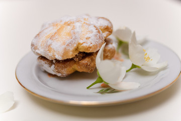 cake with jam and powdered sugar on the plate with spring jasmine flowers on the white background