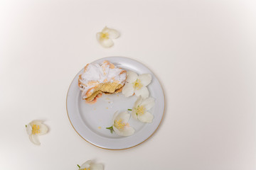 cake with jam and powdered sugar on the plate with spring jasmine flowers on the white background