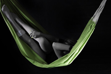 Attractive woman in white fishnet stocking relaxing in a hammock