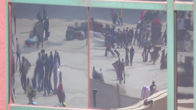 CLOSE UP: Local people and tourists walking across a square in Beijing are reflected in the windows of a modern high rise building. Distorted view of pedestrians in the reflection of a large window