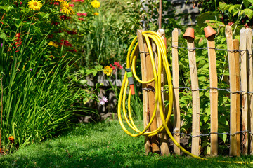 Wasserschlauch für den Garten hängt am Zaun 