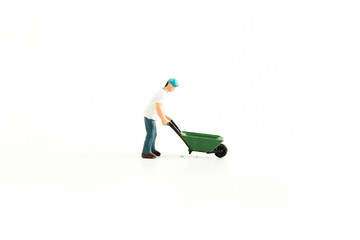 Iconic photo of a Man pushing a Wheel Barrow, Miniature person with white isolated background