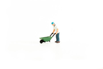 Iconic photo of a Man pushing a Wheel Barrow, Miniature person with white isolated background
