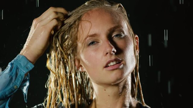 Beautiful blond woman hip-hop dancing in the rain. Slow Motion.