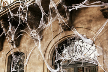 Spooky spider web on building facade in city street, holiday decoration of store fronts. Halloween street decor. Space for text. Trick or treat. Happy halloween. Autumn market