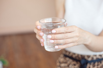 Female hands holding a clear glass of water.A glass of clean mineral water in hands, healthy drink