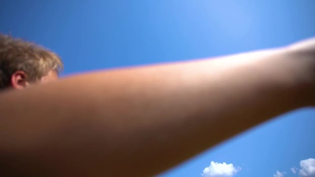 Closeup view of cte white kid playing colorful kite outdoor. Wide angle video footage of boy isolated at sunny blue sky background. Slow motion video footage.