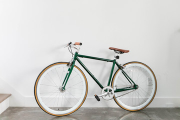 Fixed Green and Brown Bicycle in Modern Home, Fixie Bike inside hous​e, white wall background, isolated retro bicycle 