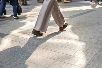 Photo of human legs in different shoes walking on the sidewalk on the street