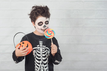 Happy Halloween.funny child in a skeleton costume eating lollipop in halloween