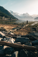 person walking along the coast in the fjord with mountains