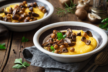 Traditional Italian polenta or boiled cornmeal with mushrooms and chickpeas garnished with fresh...