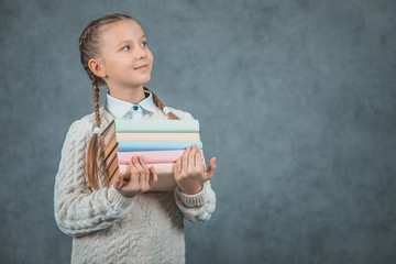 Portrait of a smart and attractive shoolgirl is isolated on grey background