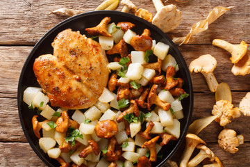 Spicy baked chicken breast with potato garnish and chanterelles close-up on the plate. horizontal top view