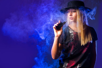 Vape. The girl in the black hat inhaling from vape. Vapor. Smoking vape. Vaping concept. E-Cigarette. Electronic Cigarette.