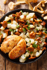 Fried chicken breast with potatoes and chanterelles close-up on a plate. Vertical top view
