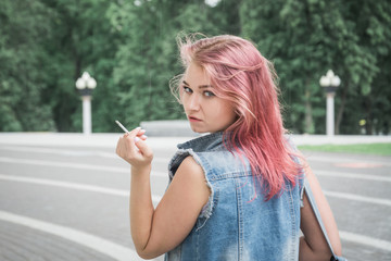 hipster girl in a denim jacket smokes a cigarette