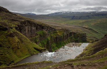 View from the top of Glymur waterfall. Green hills, high waterfall. Iceland