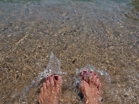 piedi femminili che si intravedono nella trasparenza dell'acqua marina