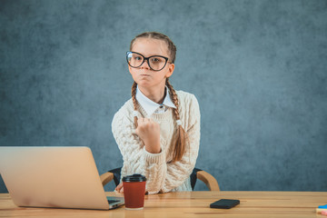 Girl in glasses on the grey background showing a fist in glasses.