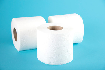 Three rolls of white toilet paper on a colored background