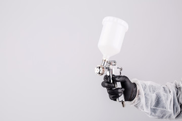 Hand and spray gun at work on white background
