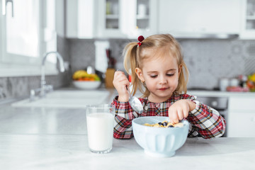 Young girl drinking milk and eat healthy breakfast at the kitchen table