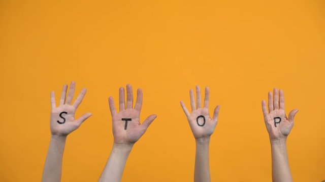 Stop written palms on orange background, danger warning, protest expression