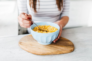 healthy breakfast concept - close up of corn flakes with blueberry in glass bowl and female hands