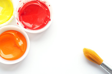 tassel with wooden handle and three caps with orange yellow and red paint on a white blank sheet of paper..
