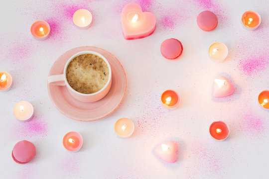 cup of coffee with burning candles on pink painted paper backgro