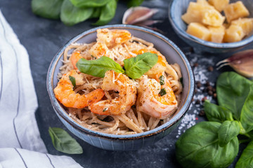 Pasta with shrimps in a plate, close-up, copy space, top view. Pasta cooking concept, ingredients and spices on a table with a dish.