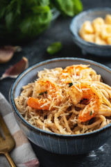 Pasta with shrimps in a plate, close-up, copy space, top view. Pasta cooking concept, ingredients and spices on a table with a dish.