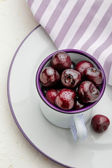 Close-up of fresh cherries in white porcelain cup. On pink fushia background. Space to insert text.