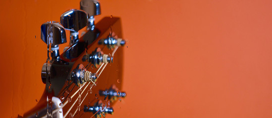 guitar headstock with tuning pegs  behind .the glass with water drops