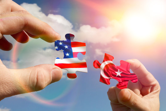 Two hands assemble a puzzle with the flags of Turkey and America. partnership, commonwealth, agreement