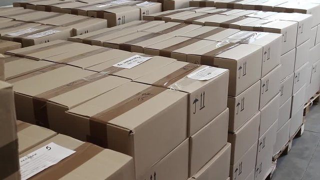 Stacks of cardboard boxes in the warehouse of the factory. Products in the warehouse stacked in large piles in cardboard boxes, close-up. Logistics center with cardboard boxes on the enterprise.