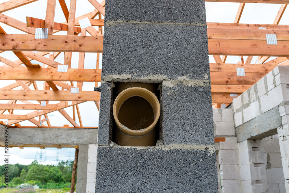 Wall mural System chimney on a detached house under construction, visible chimney block and elements of roof trusses.