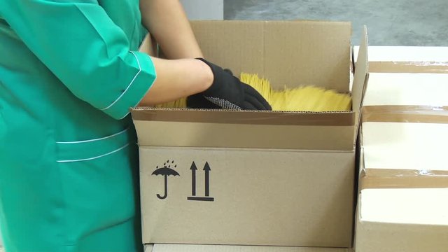 Packing pasta at the factory. Line for packaging pasta in plastic bags. Worker packs spaghetti in cardboard boxes. Large cardboard boxes with spaghetti. Packing workshop at a pasta factory.