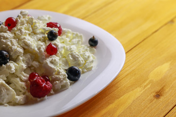 Plate with cottage cheese and fresh berries on wooden table