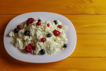 Plate with cottage cheese and fresh berries on wooden table