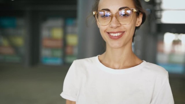 close-up portrait of young smiling fashionable beautiful woman in transparent eyewear posing outdoors. slow motion 4K stock footage