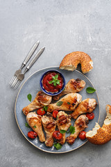 Grilled chicken drumstick with tomato sauce and greens on a gray background. Top view, flat lay, copy space.