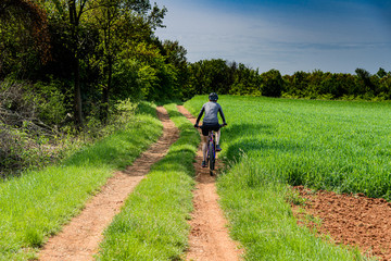 Obraz premium Woman with bike rides on the dirt road