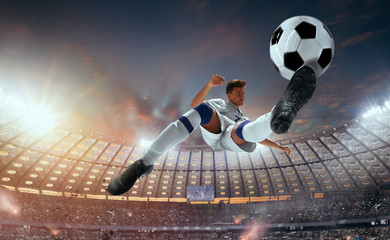 Soccer players in action on professional stadium on sunset.