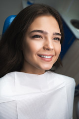 happy young woman patient lying on dental chair under the medical lamp in clinic