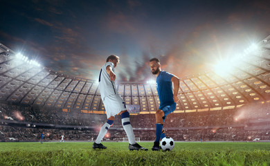 Soccer players in action on professional stadium on sunset.
