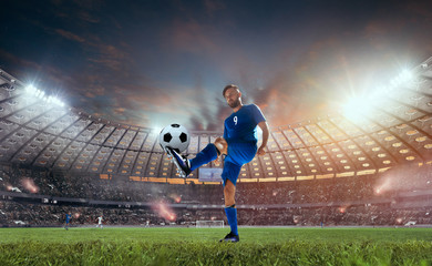 Soccer players in action on professional stadium on sunset.