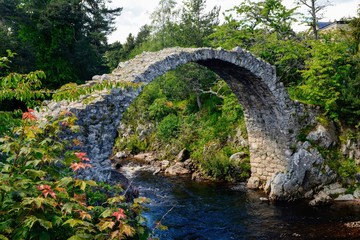 Fototapeta na wymiar Old Packhorse bridge in Carrbridge, Scotland, built in 1717. It is the oldest stone bridge In Scottish Highlands.